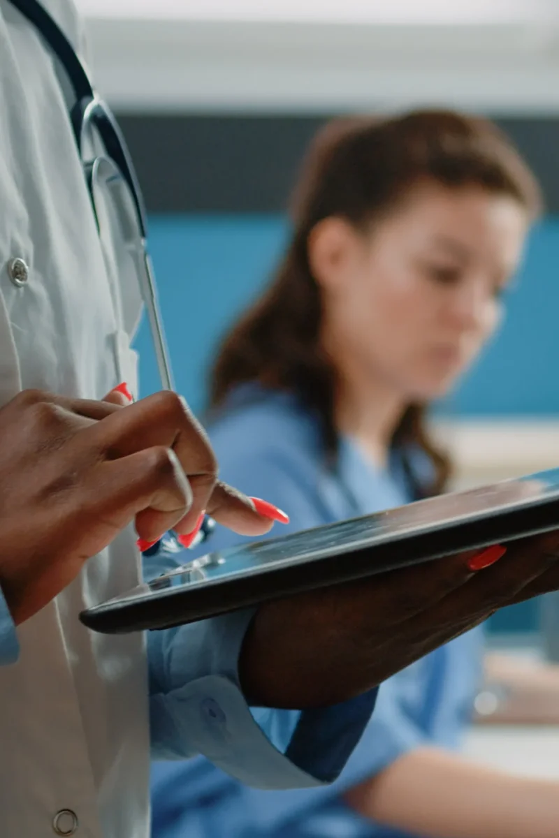 close-up-african-american-doctor-using-tablet-with-touch-screen-healthcare-information-cabinet-black-medic-with-white-coat-stethoscope-holding-modern-gadget-medical-care (1)